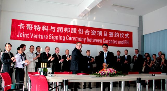 Ilkka Herlin, chairman of the board, Cargotec (left) and Wu Jian, chairman of Jiangsu Rainbow Heavy Industries (right) shaking hands at the signing ceremony (Cargotec and RHI employees in the background).
