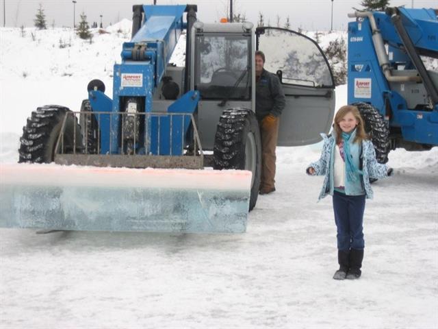 Genie telehandler holds ice block while Tavia Wilson and Dave Mason anticipate sculpturing to come.