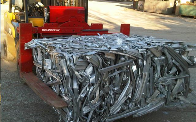 Bolzoni fork clamp with metal scrap: first the metal is sorted, than it goes in the shredder machine and afterwards waste metal bales are ready to be handled.