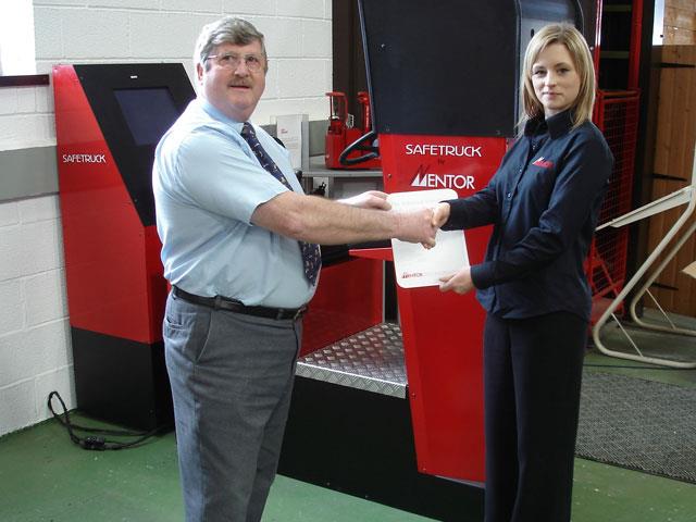 Jim Brindley receiving the Safetruck simulator from Emily Gregory, Mentor's marketing manager, in an official ceremony last month.