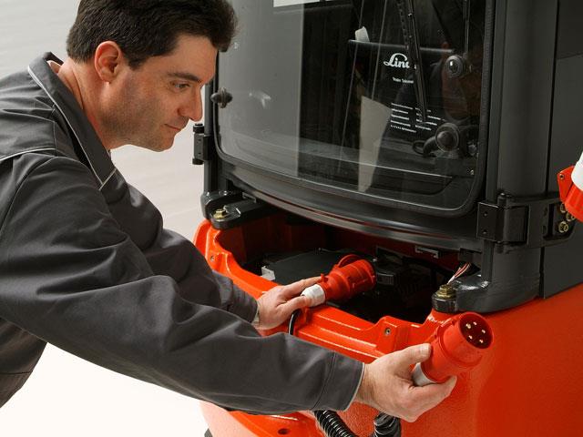 A forklift operator charging a Linde counterbalanced forklift's battery with the onboard battery charger.