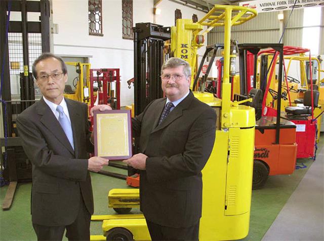 Kazuhiko Hirai presents the plaque to James Brindley (Komatsu reach truck in background).