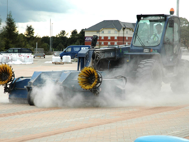 Telehandler with sweeper attachment.