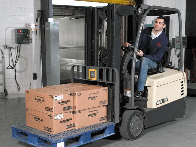 An RFID-enabled Crown SR 4500 three-wheel counterbalanced forklift is demonstrated in a warehouse setting. Symbol's RD5000 reader, a predecessor of the upcoming RFS7000 RF, is at the base of the forklift, just above the boxes.
