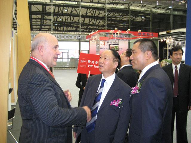 (L-R) John B Nofsinger, CEO of Material Handling Industry of America shakes Ding Junfa's hand while James Fu, general manager of Hannover Fairs China Ltd looks on.