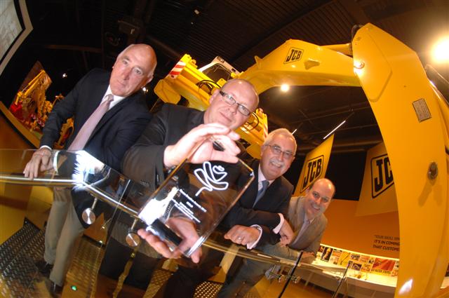 JCB Worldwide Head of Creative Steve Brazier holds the Roses trophy. Looking on are, left to right, The Story of JCB project delivery managers Colin Bond and Geoff Bourne and JCB Worldwide marketing director Matt McClurg.